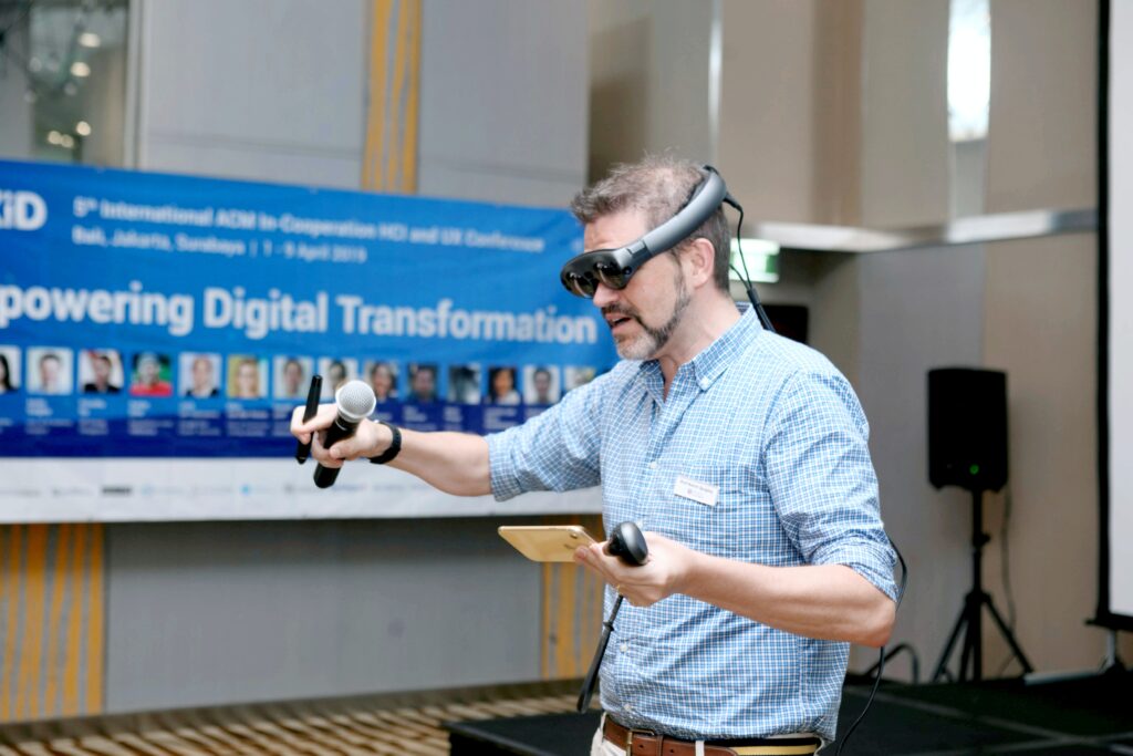 Man wearing VR set and giving a presentation with Empowering Digital Transformation in the background