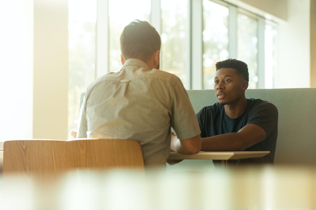 Two people having a conversation while sitting at a wooden table 