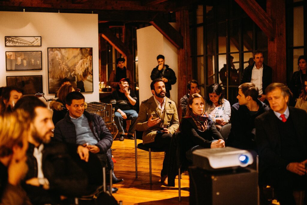 Audience engaged with a speaker giving a presentation in a gallery